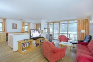 a living room with red chairs and a flat screen tv at Schöneben Haus Sonneck in Wald im Pinzgau