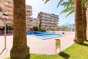 a swimming pool in front of a building with palm trees at Rentalmar Murillo Plus in Salou