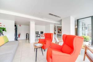 a living room with orange chairs and a table at Brit Hotel Porte d'Espagne in Perpignan