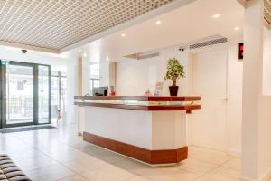 a lobby with a counter with a potted plant at Brit Hotel Porte d'Espagne in Perpignan