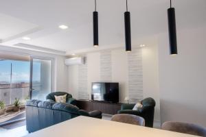 a living room with a table and chairs and a tv at Mellieha, Charming 2 Bedroom Apartment Santa Maria Heights Mellieha in Mellieħa