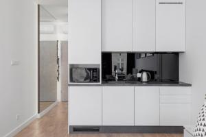 a kitchen with white cabinets and a microwave at Selenite - Studio with Balcony & AC - City Center in Krakow +8 photos