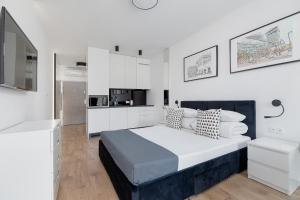 a white bedroom with a large bed and a kitchen at Selenite - Studio with Balcony & AC - City Center in Krakow