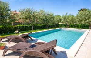 a swimming pool with two chairs and a table at Lovely Home In Medulin With Wifi in Medulin +30 photos