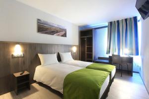 加来Brit Hotel Calais的一间酒店房间，配有一张大床和一张书桌