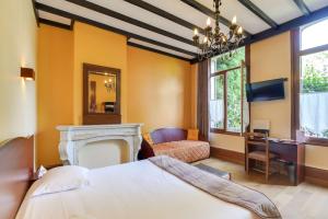a bedroom with a bed and a chair and a fireplace at Brit Hotel Notre Dame in Valenciennes