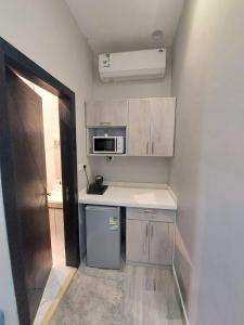 a small kitchen with white cabinets and a microwave at Modern Family Apartments 7 Mins Drive to Al Masjid Nabwi in Medina