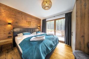 a bedroom with a large bed with a blue blanket at Nationalpark Chalet Kreuzkogel in Neukirchen am Großvenediger