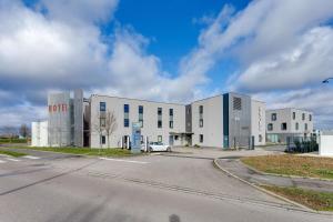 a large white building with a car parked in front of it at Brit Hotel Confort Saint-Dizier in Saint-Dizier