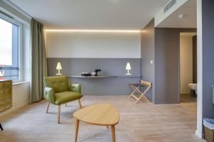 a living room with a green chair and a table at Brit Hotel Confort Saint-Dizier in Saint-Dizier