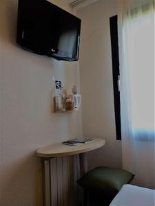 a room with a small table and a tv on the wall at Brit Hotel Essentiel de Granville in Granville
