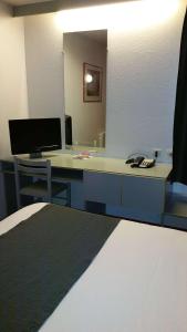 a room with a desk with a computer and a mirror at Brit Hotel Sarreguemines in Sarreguemines