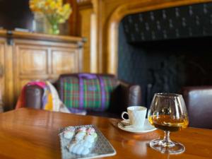 a wooden table with a glass of wine and a plate of candy at Brit Hotel Du Dauphin L'Aigle in LʼAigle