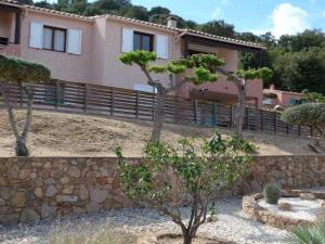 a house with a stone wall and trees in a yard at Domaine San Sebastiano in Porto-Vecchio