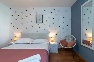 a bedroom with a white bed and a chair at Villa Alina with heated pool in Rogoznica +50 photos