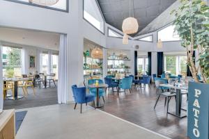 a restaurant with blue chairs and tables and windows at Brit Hotel Au Pays De Vitré in Étrelles