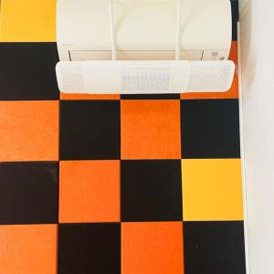 オルビアにあるVicino Aeroporto - Orange Marina Roomのオレンジ、黒、オレンジのチェック柄の床のベッド