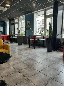 a lobby with tables and chairs and plants at Brit Hotel Mulhouse Centre in Mulhouse
