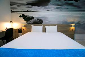 a bedroom with a large bed with a painting on the wall at Brit Hotel Le Polder in Gravelines