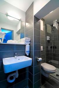 a bathroom with a sink and a toilet and a mirror at Brit Hotel Le Polder in Gravelines