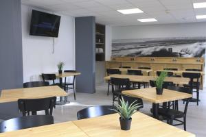 a dining room with tables and chairs and a tv on the wall at Brit Hotel Le Polder in Gravelines