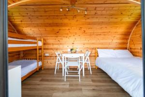 a room with two beds and a table in a cabin at Camping Pods Wood Farm Holiday Park in Charmouth