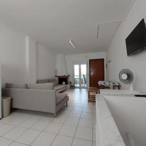 a white living room with a couch and a tv at Olive Tree Villa in Nikiti