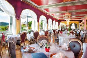 un restaurante con mesas y sillas blancas y ventanas en Hôtel Beau Site, en Malbuisson