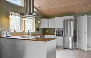 a kitchen with white cabinets and a stainless steel refrigerator at Bakkely in Brønde