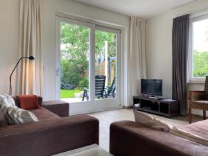 Una sala de estar con un sofá y un televisor. en Previnaireweg 30, en Callantsoog