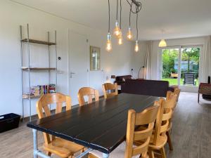 comedor con mesa negra y sillas de madera en Previnaireweg 30, en Callantsoog