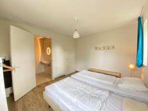 1 dormitorio con 2 camas blancas y baño en Previnaireweg 30, en Callantsoog