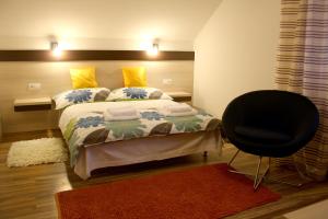 a bedroom with a bed and a black chair at Guest House Vila Pod Lesom in Bystrá