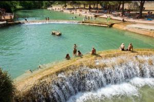 a group of people in a swimming pool next to a waterfall at Appartement Cosy Loft in Salernes
