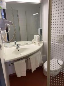 a bathroom with a sink and a toilet and a mirror at Brit Hotel Confort Montauban in Montauban +100 photos