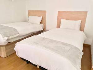 two beds in a room with white sheets and pillows at Apto La Muralla Centro - Playa in Gijón