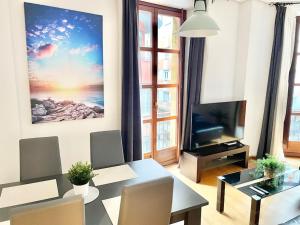 a living room with a dining table and a television at Apto La Muralla Centro - Playa in Gijón +36 photos