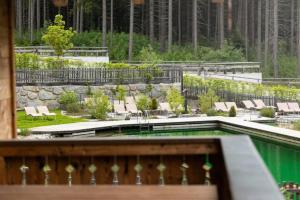 a garden with a pool and chairs and trees at Nationalpark Chalet Blindis in Neukirchen am Großvenediger