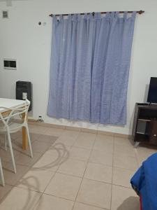 a room with a table and a blue curtain at Remedios de Escalada suite 2 pb in Villa María