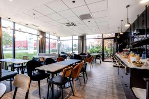 a restaurant with tables and chairs and windows at Brit Hotel Du Stade Rennes Ouest in Rennes