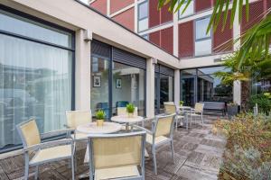 a patio with tables and chairs in front of a building at Brit Hotel Du Stade Rennes Ouest in Rennes