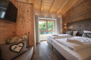 a bedroom with two beds and a large window at Nationalpark Chalet Rosenspitze in Neukirchen am Großvenediger