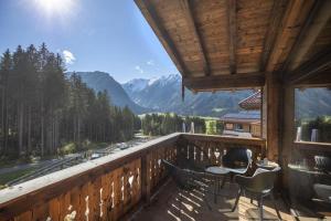 a balcony with a table and chairs and mountains at Nationalpark Chalet Säulspitze in Neukirchen am Großvenediger