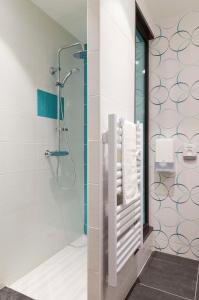 a bathroom with a shower and towels on a wall at Brit Hotel Privil&egrave;ge Figeac in Figeac