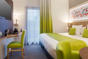 a hotel room with a bed and a desk and a table at Brit Hotel Privil&egrave;ge Figeac in Figeac