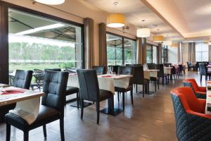 a restaurant with tables and chairs and a large window at Brit Hotel Privil&egrave;ge Figeac in Figeac