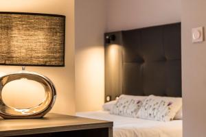 Un dormitorio con una cama con un espejo sobre una mesa. en Brit Hotel Confort Foix, en Foix