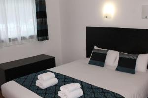 a bedroom with a large bed with towels on it at Brit Hotel MOTEL - Lyon L'Arbresle in LʼArbresle +1 photo