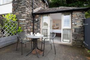 a table and chairs in front of a stone building at The Lakehouse Rooms at The Waterhead Inn, Ambleside in Ambleside