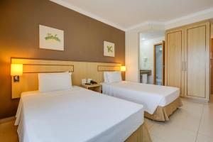 two beds in a hotel room with white sheets at Comfort Franca in Franca